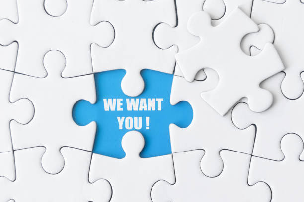 White puzzle with one missing piece shows: WE WANT YOU! stock photo