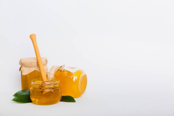 istock Honey in jar with leaves and honey dipper on colored background top view with copy text 1442738414