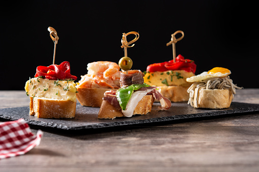 Assortment of Spanish pintxos on wooden table on black background