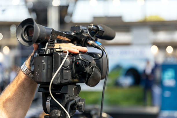 istock Camera operator filming media event, news or press conference with a professional video camera 1442742834