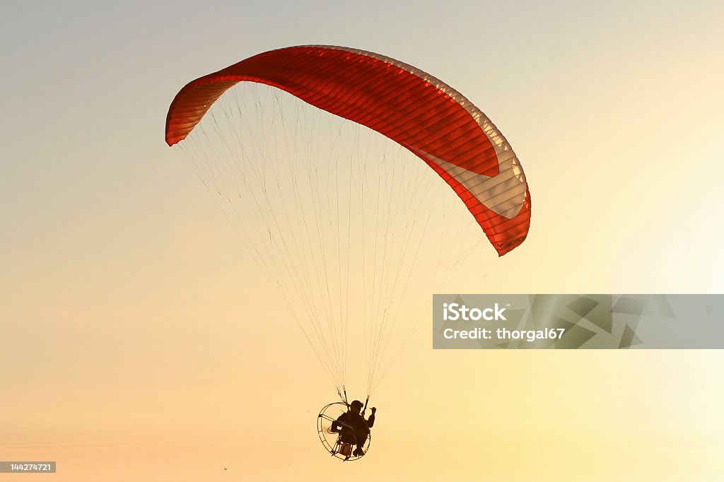 Red parachute flying at sunset Picture of a powered paraglider flying into the sunset Aerial View Stock Photo