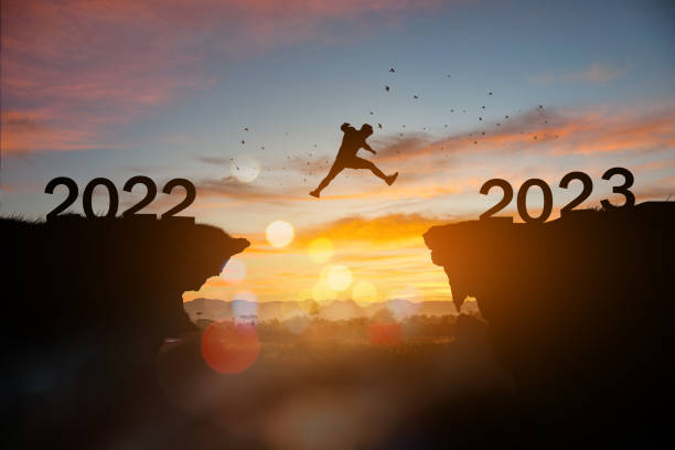 Silhouette the Man jump to the New Year 2023 at sunset. stock photo