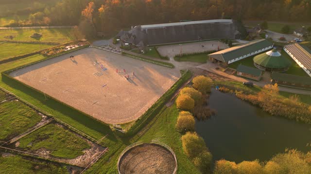 Aerial view of horse rider and horse on training ground at sunset.