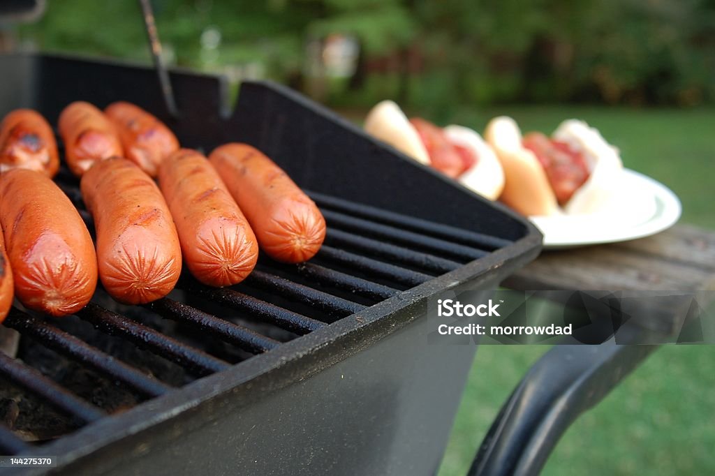 Barbeque Grill filled with hot dogs Barbeque Grill filled with hot dogs, finished plate in background. Barbecue Grill Stock Photo