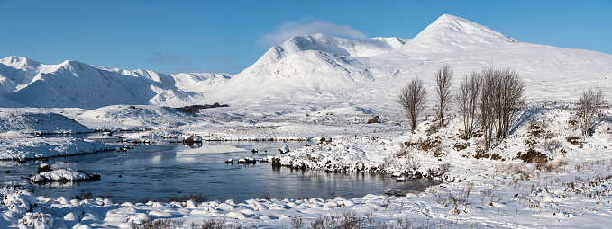 Majestic Winter landscape image looking towards Scottish Highlands mountain range across Loch Ba on Rannoch Moor