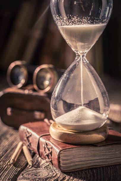istock Vintage hourglass and journal with binocular, books and compass. 1442763131