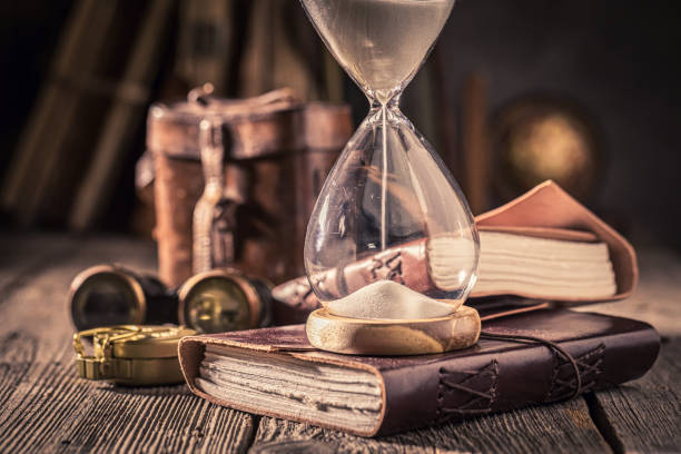 istock Old hourglass and journal as a journey memories concept. 1442763234
