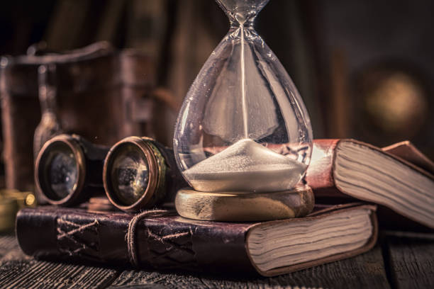 istock Aged hourglass and journal with binocular, books and compass. 1442764288