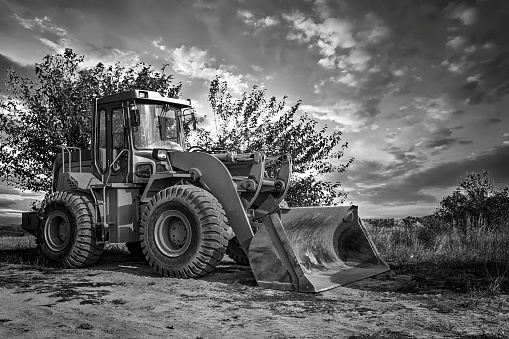 A bulldozer or loader moves the earth at the construction site against the sky