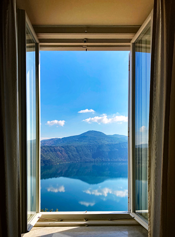 Room with window with view to autumn forest and lake. landscape with lake in forest. Panoramic view to nature from room window. window of cozy room overlooking forest lake