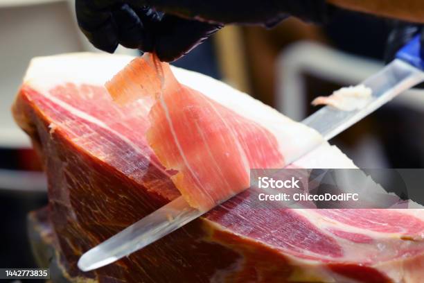 Hand Of The Butcher Who With A Sharp Knife Slices A Slice Of Raw Ham Stock Photo - Download Image Now