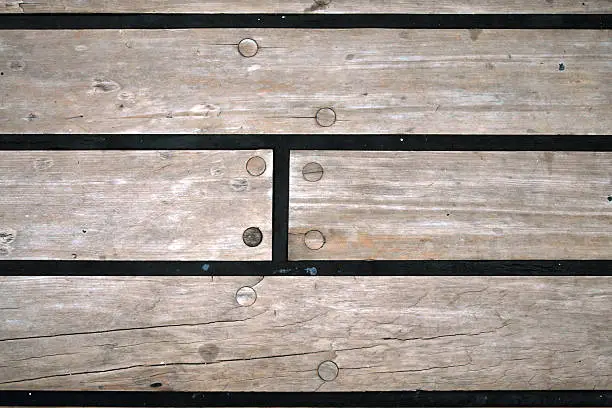 A wooden floor with screws and rubber sealing on the deck of a ship