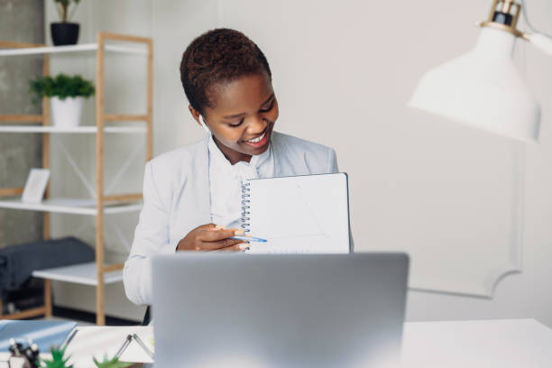 istock African woman sitting at office table sharing her project idea with friends by videoconference app. Business people lifestyle. Internet communication. Internet network. Online remote video conference call. 1442780347