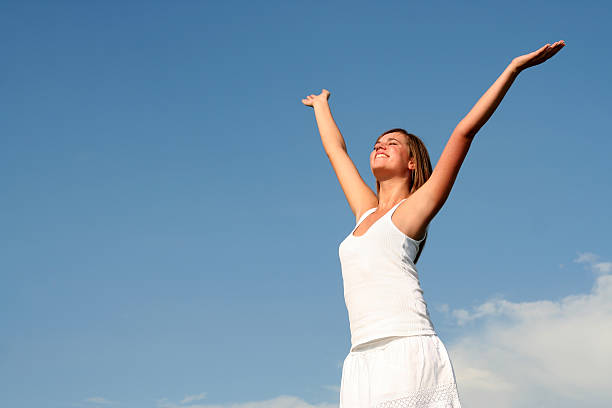 istock A woman in white spreading arms under a blue daytime sky 144278290