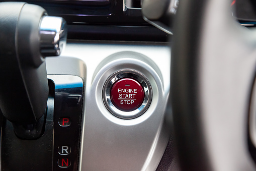 Red Button start and turn off the ignition of the car engine close-up on the dashboard, electric key, of modern design black and with elements chrome on the interior panel. Auto service industry.
