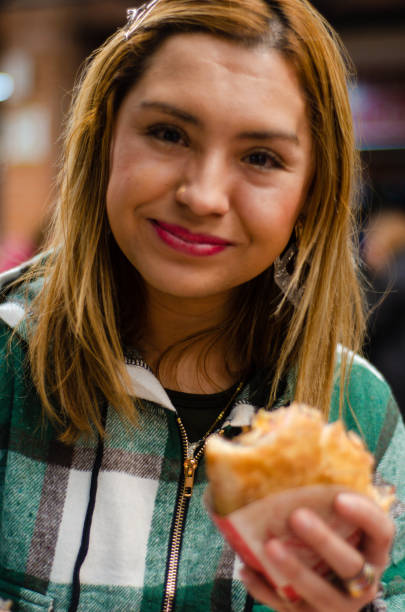 istock Woman smiling and eating a hamburger looking at camera 1442785071