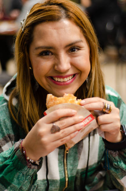 istock Woman smiling and eating a hamburger looking at camera 1442785089