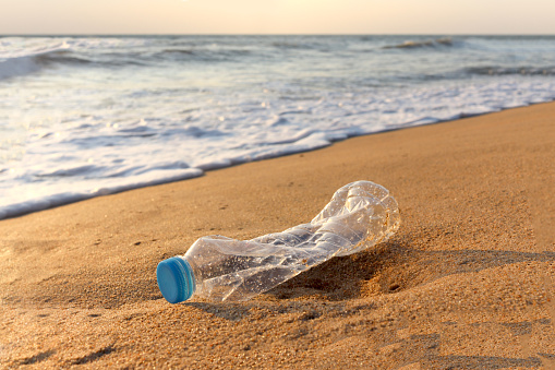 Plastic bottle garbage waste ying on sand beach, garbage rubbish on beach and marine sea pollution concept.