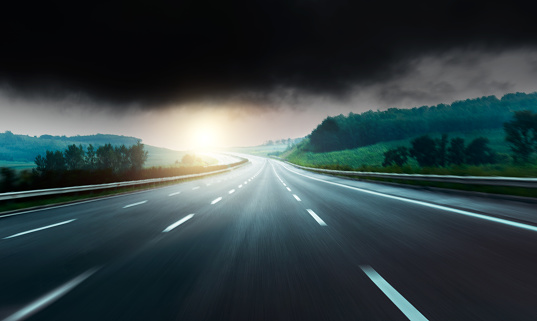 Motion blur of empty highway road against stormy clouds