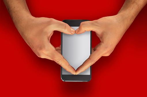 Holding and making a heart shape on a mobile phone