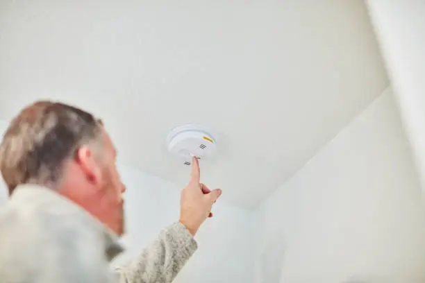 Photo of Male home inspector checking a smoke and carbon monoxide detector during the home inspection of a residential property