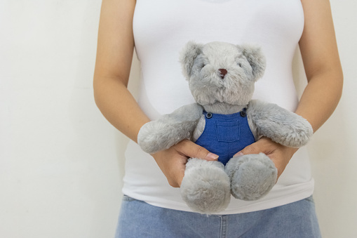 Close up pregnant woman holding teddy bear. Concept of pregnancy, Asian Young mother waiting of the baby.