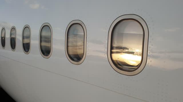 Close up of airplane exterior portholes and rivets at dusk. Panning