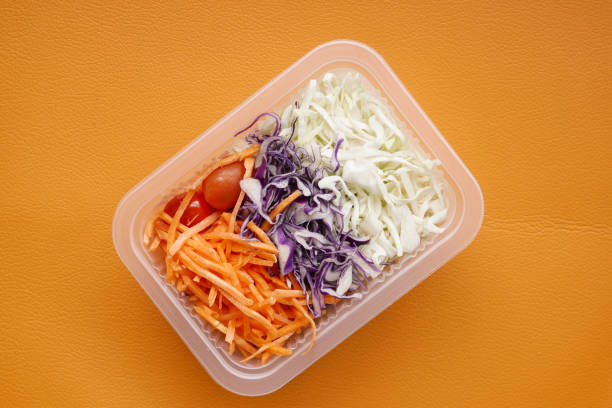 istock fresh vegetable salad in a plastic container on orange background 1442795605
