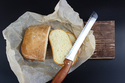 Sliced bread on a wooden cutting board and knife. Sourdough Loaf sliced with bread knife.