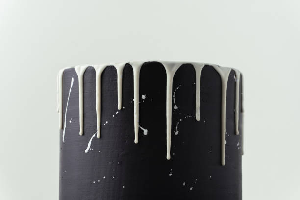 istock Black cake with white chocolate drips on the white background. Pouring chocolate on the cake. Chocolate drops on the cake 1442804364