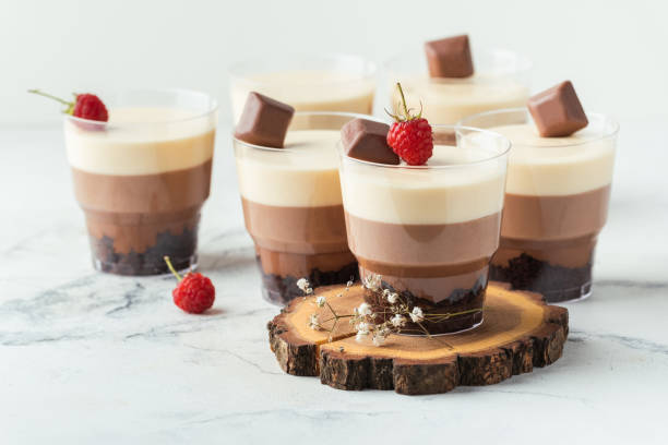 istock Layered dessert Trifles in a transparent glass.  Sponge biscuit and three chocolate mousse layers. Chocolate souffle trifle cake in individual disposable transparent cups. White background 1442804437
