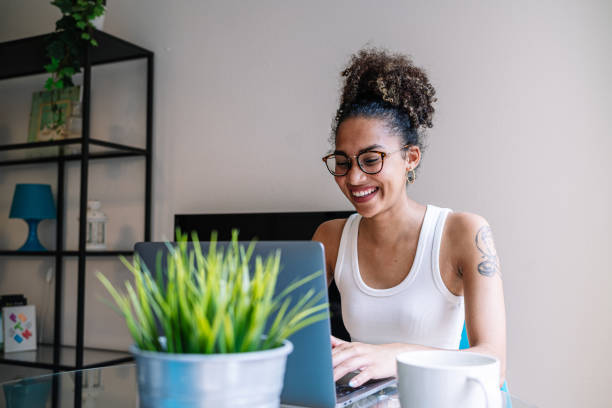 istock Cheerful black woman using laptop in home office 1442806988