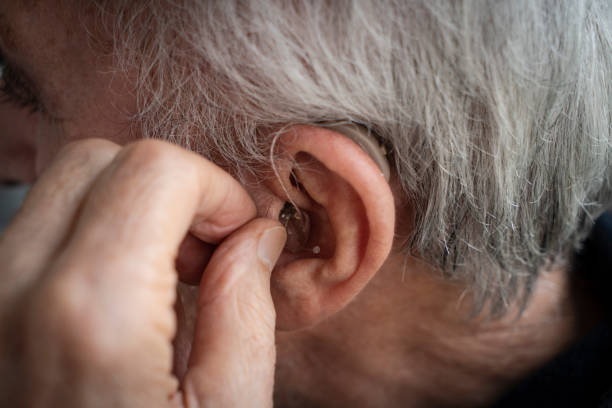 Elderly Man Inserting His Hearing Aid Elderly Man Inserting His Hearing Aid ear horn photos stock pictures, royalty-free photos & images