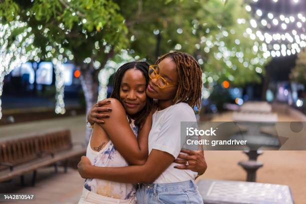 Two African-American Twin Sisters in Their Twenties Embracing Each Other Lovingly with Happy Smiles