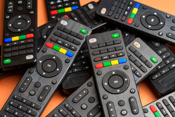 a bunch of remotes dumped randomly on top of each other. many TV remotes