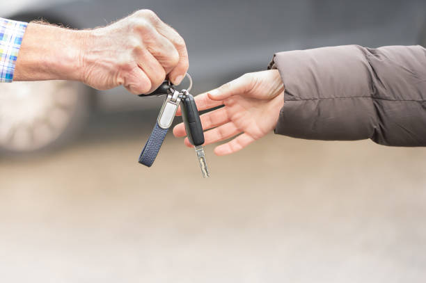 car key hands over Businessman  a woman in front of blurred car stock photo