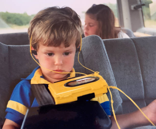 Family Car trip 1990 Little Boy Listening to Cassette Player Little boy and big sister in van for car trip 1990. vehicle interior audio stock pictures, royalty-free photos & images