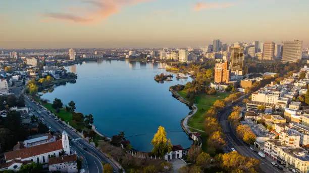 Aerial stock photo of downtown Oakland California and Lake Merritt early in the morning at sunrise.