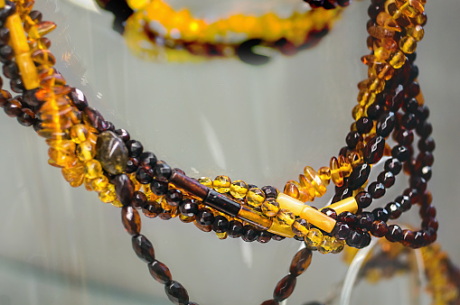 Various amber beads on a glass shelf. Close up.