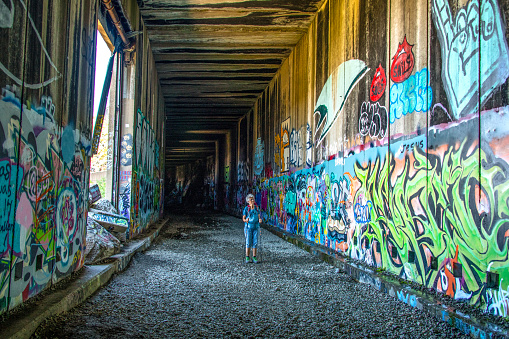 A hiker is exploring the graffiti art inside one of the abandoned rail tunnels on Donner Summit. The original Central Pacific line, opened in 1887, was later covered with these 