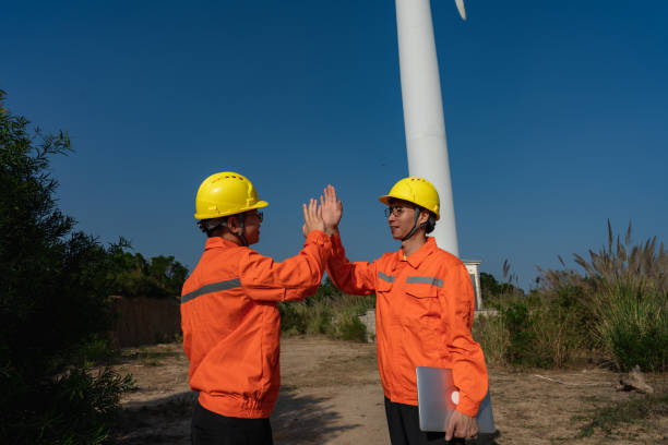 dos ingenieros eléctricos junto a un molino de viento - looking away power occupation young adult technology fotografías e imágenes de stock
