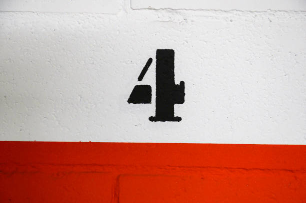 istock Number 4 four painted in black with a stencil and spray paint on a white block wall in a garage, below a strip of red line 1442820516