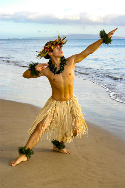 Male Hula Dancer performing on the beach next to the waters edge. stock photo