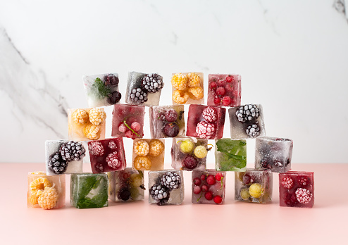 Frozen ice cubes with various berries, blackberries and raspberries, gooseberries and currants, blueberries and mint