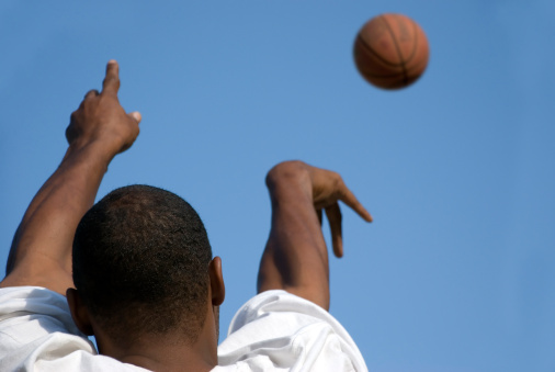Kid playing basketball, taking a shot.