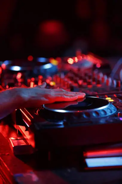 Photo of Party dj playing music in night club with professional cd turntables. Disc jockey mixing musical tracks on concert stage