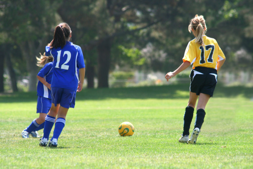 Young girls running after the ball in a soccer match