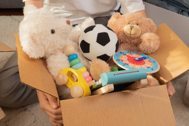 Teenager sorting and collect kid toys, clothes into boxes at home. Donations for charity, help low income families, declutter home, sell online, moving into new home, recycling, sustainable living stock photo