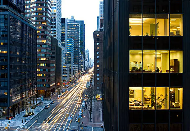 Picture of a busy street in Manhattan, New York City. The traffic moves busily below as people work in the offices above.