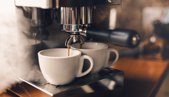 La máquina Portafilter vierte café fresco en tazas de capuchino photo